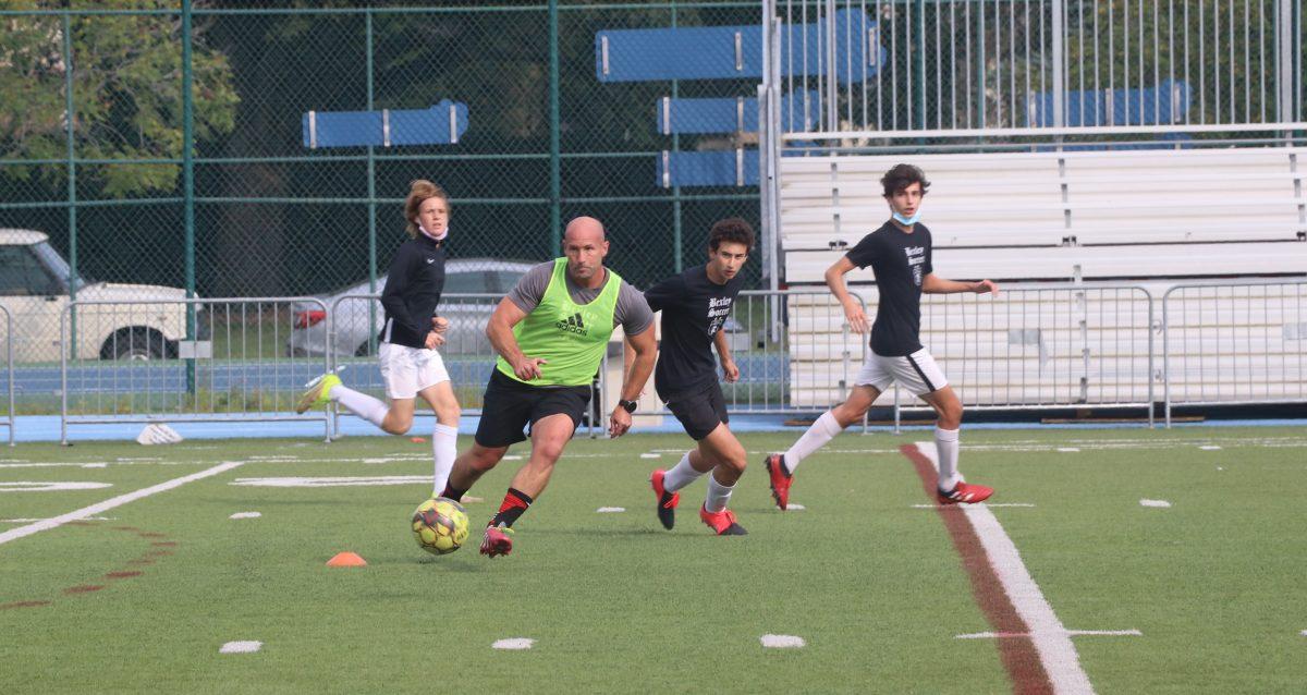 New boys soccer coach Jason Goggins participates in drills with team members during practice. (photo by Talia Kahan)