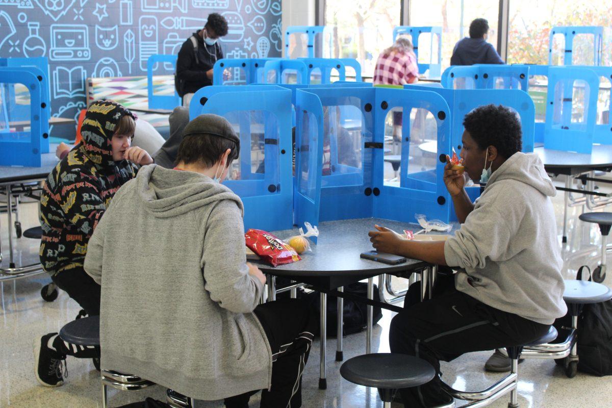 Freshmen students Christian Peters (left), Lorenzo Price (center), and Darrel Milton Jr. (right), eat lunch in the cafeteria following the implementation of the new Covid guidelines. (Photo by Theo Weinstock)