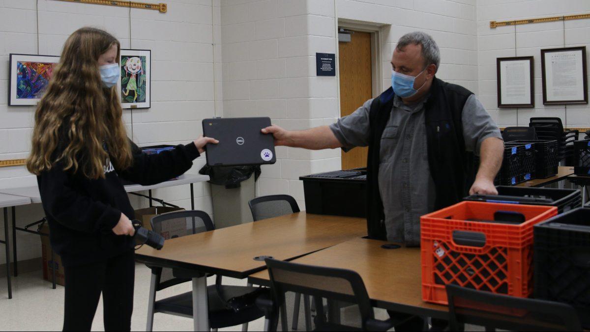 Director of English Resource Center Neal Tomich hands Freshman Harper Phillips a Chromebook from the 1:1 Chromebook initiative funded by the BEF. (Photo by Zach Trabitz)