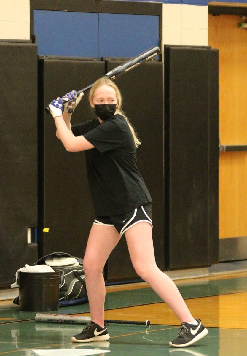 Senior Olivia Wilson prepares to hit the softball during training for the upcoming season. (Photo by Harley Carroll)