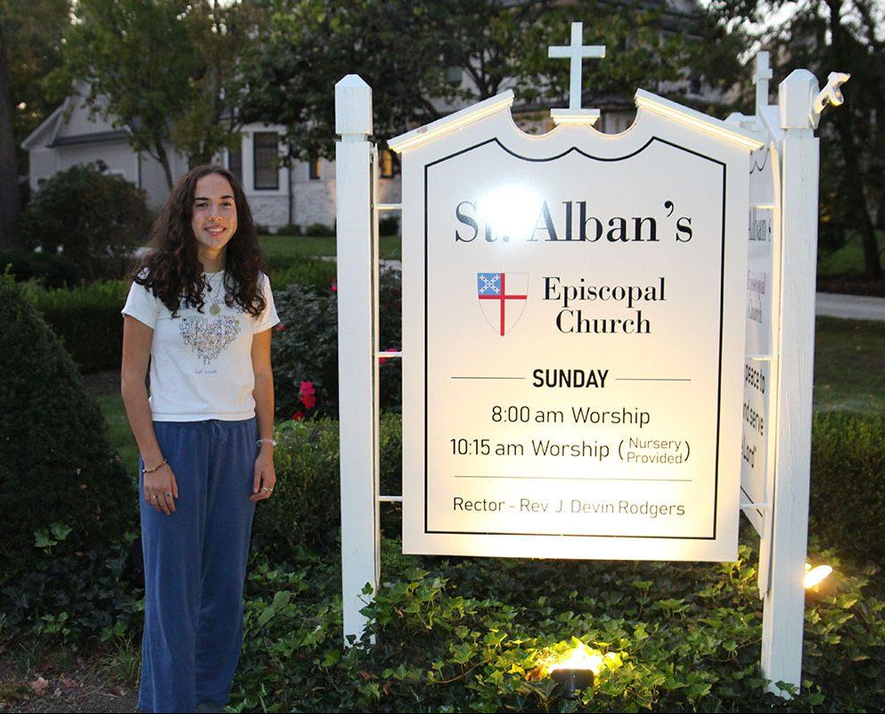 Senior Claire MacDonald stands beside the sign at St. Alban's Episcopal Church. (Photo by Katie Jude)