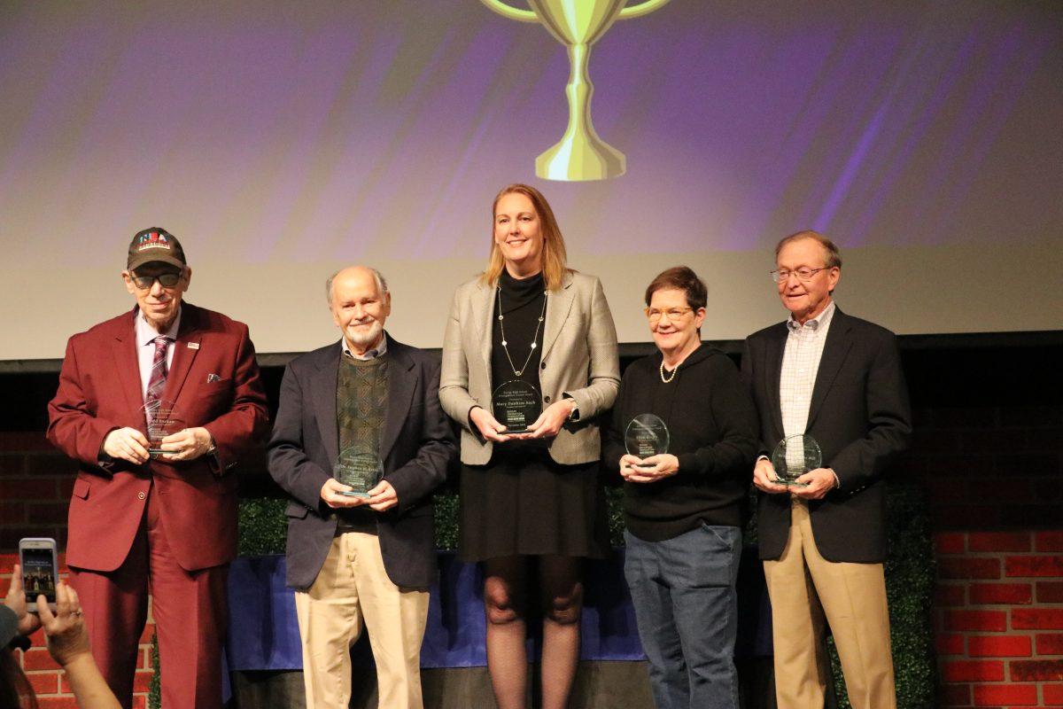 Todd Barkan, Stephan Kress, Mary Dunham Auch, Ellen Klages and Bruce Meyer hold up plaques naming them Distinguished Alumni at an assembly for upperclassmen Monday, Nov. 21. (Photo by Bella McMaster)