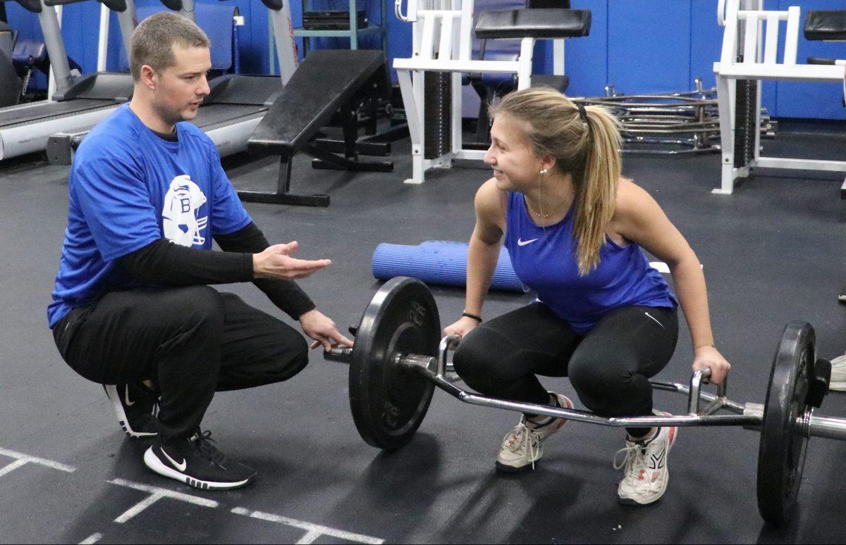 Jesse Padgett helps instruct senior Pauline Vidal on the proper deadlifting form during her preseason lacrosse lift. (Photo by Elliot Larky)