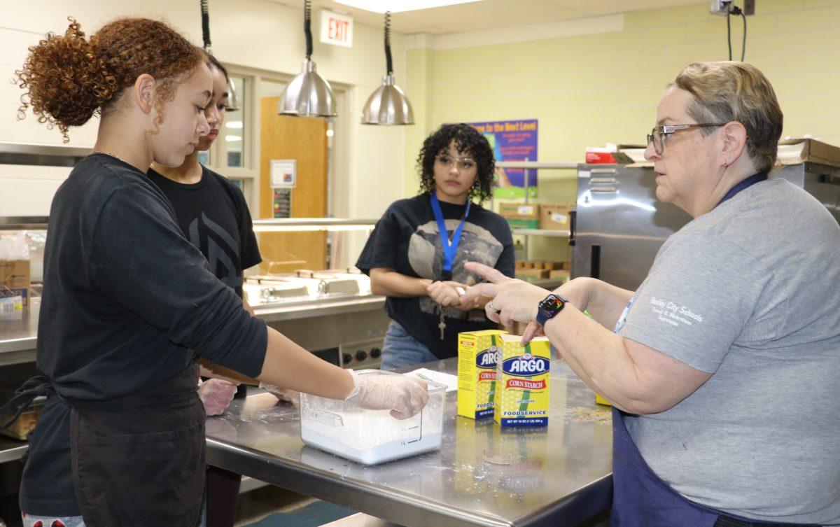 Middle school students Tovah Fliegel and Claire Boakye help prepare the Black History Month lunch with social studies teacher Dianne Day and food services director Julianna Carvi. (Photo by Elliot Larky)