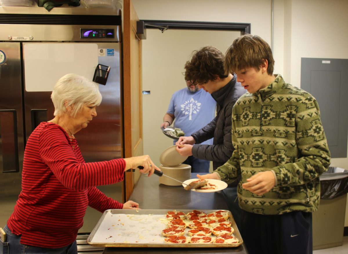 Volunteer Sharon Seckel serves juniors Noah Gardner and Rocco Isaly.