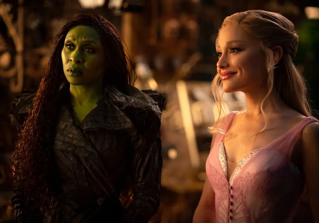 Elphaba (Cynthia Erivo) and Glinda (Ariana Grande) gaze pensively at the Wizard of Oz (Jeff Goldblum) as he performs the song “Wonderful.” (Fair use IMDb)