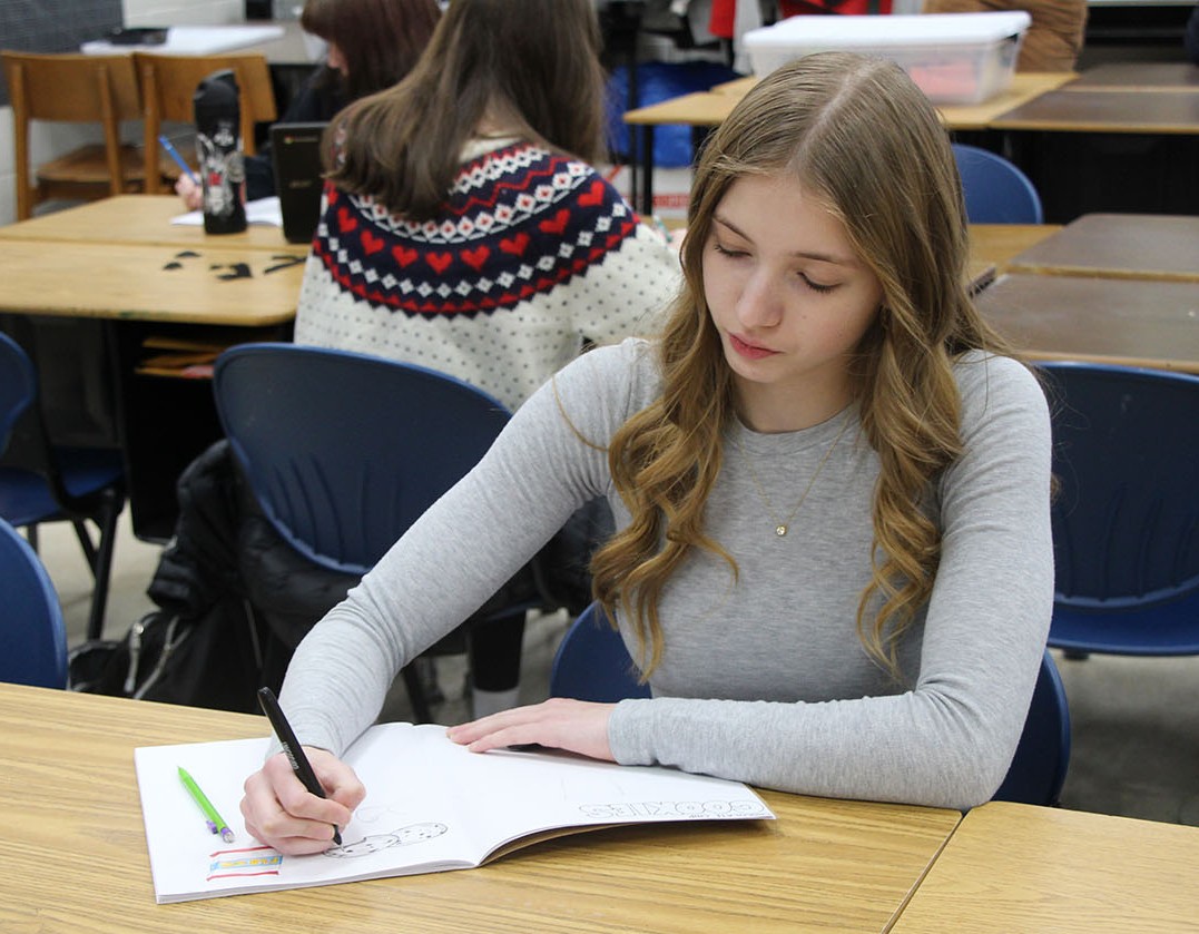 Freshman Elizabeth Levy illustrates a picture for the Community Cookbook in Rachelle Howland's drawing class.