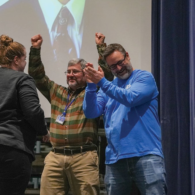Intervention specialist Ericka Rogers, science teacher Scott Logsdon and math teacher Jason Willcoxon celebrate students correctly identifying Willcoxon’s high school photo in a competition at the Renaissance assembly Friday, Jan. 16.